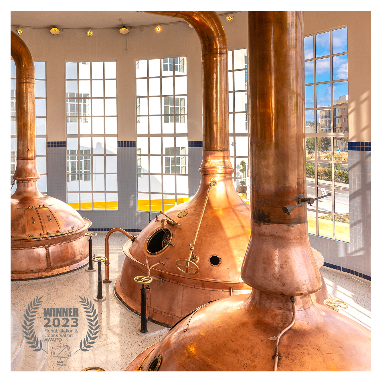 Interior view of The Brewhouse building featuring restored copper kettles, winner for the Malta Architecture and Spatial Planning Awards in the Rehabilitation & Conservation category